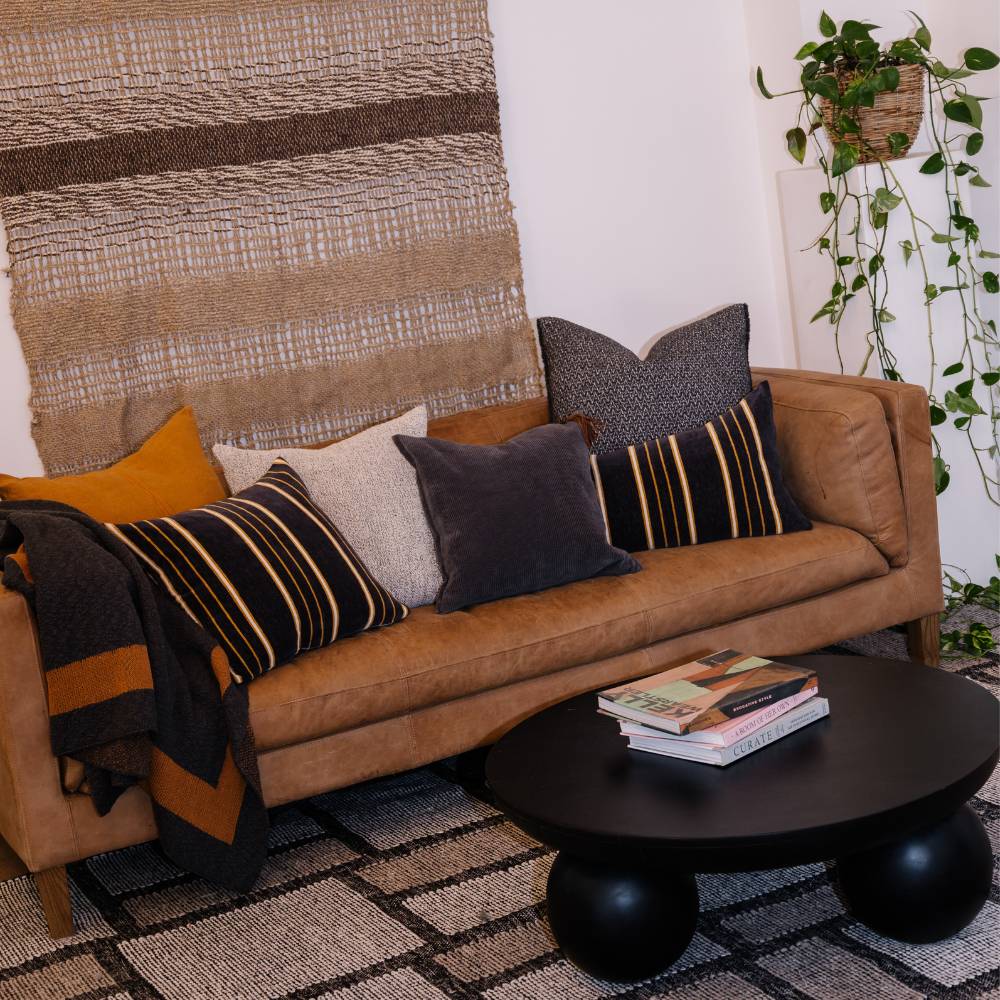 Brown leather sofa with patterned cushions in a living room setting.