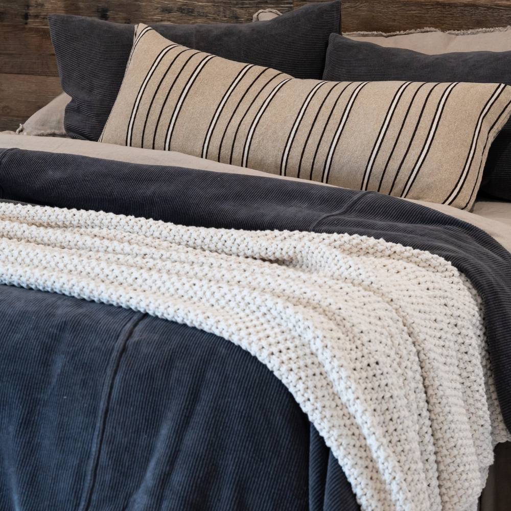 Cozy bed with striped pillow and knitted blanket