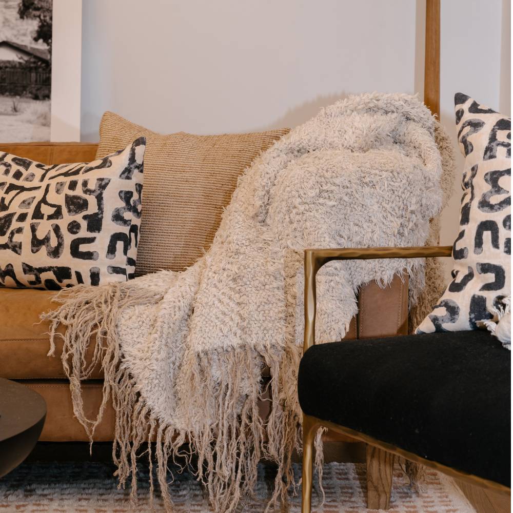 Cozy living room with a beige sofa, patterned cushions, and a textured throw blanket.