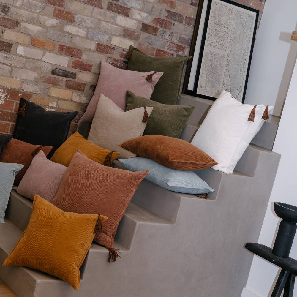 Colorful pillows on a staircase against a brick wall