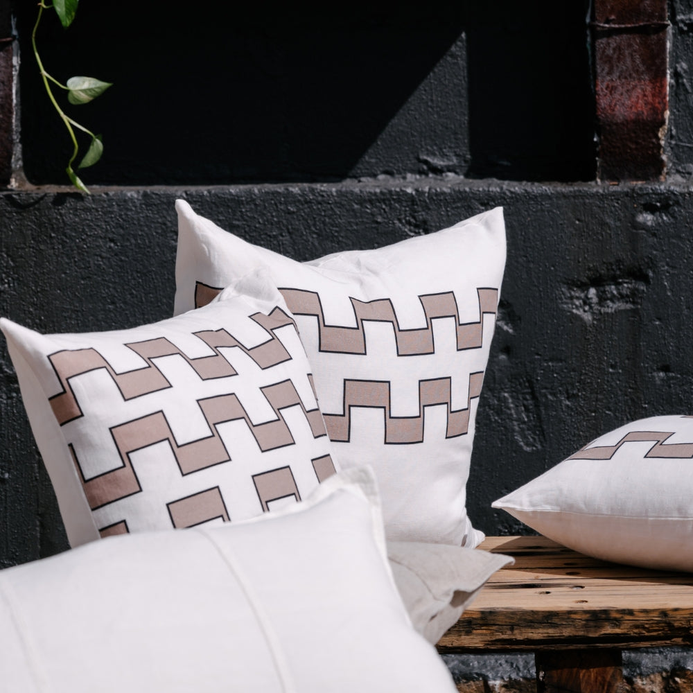 Decorative rectangular pillow with 2 lines of brown geometric pattern on a white background