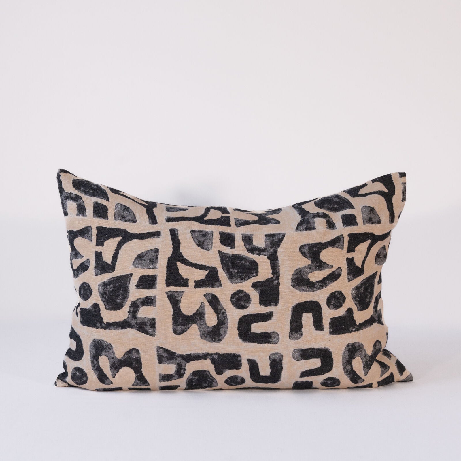 Decorative rectangular pillow with black abstract pattern on beige background