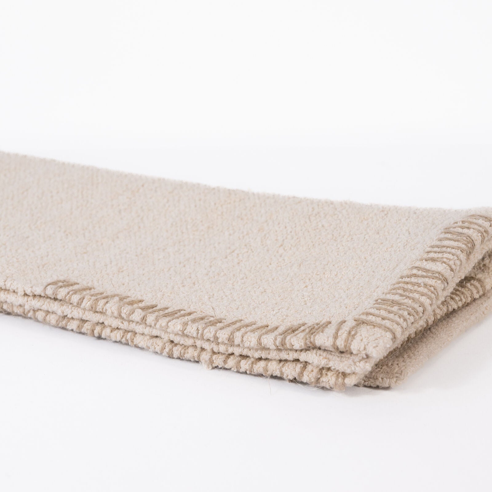 Cream or off white woven bathmat on a white background