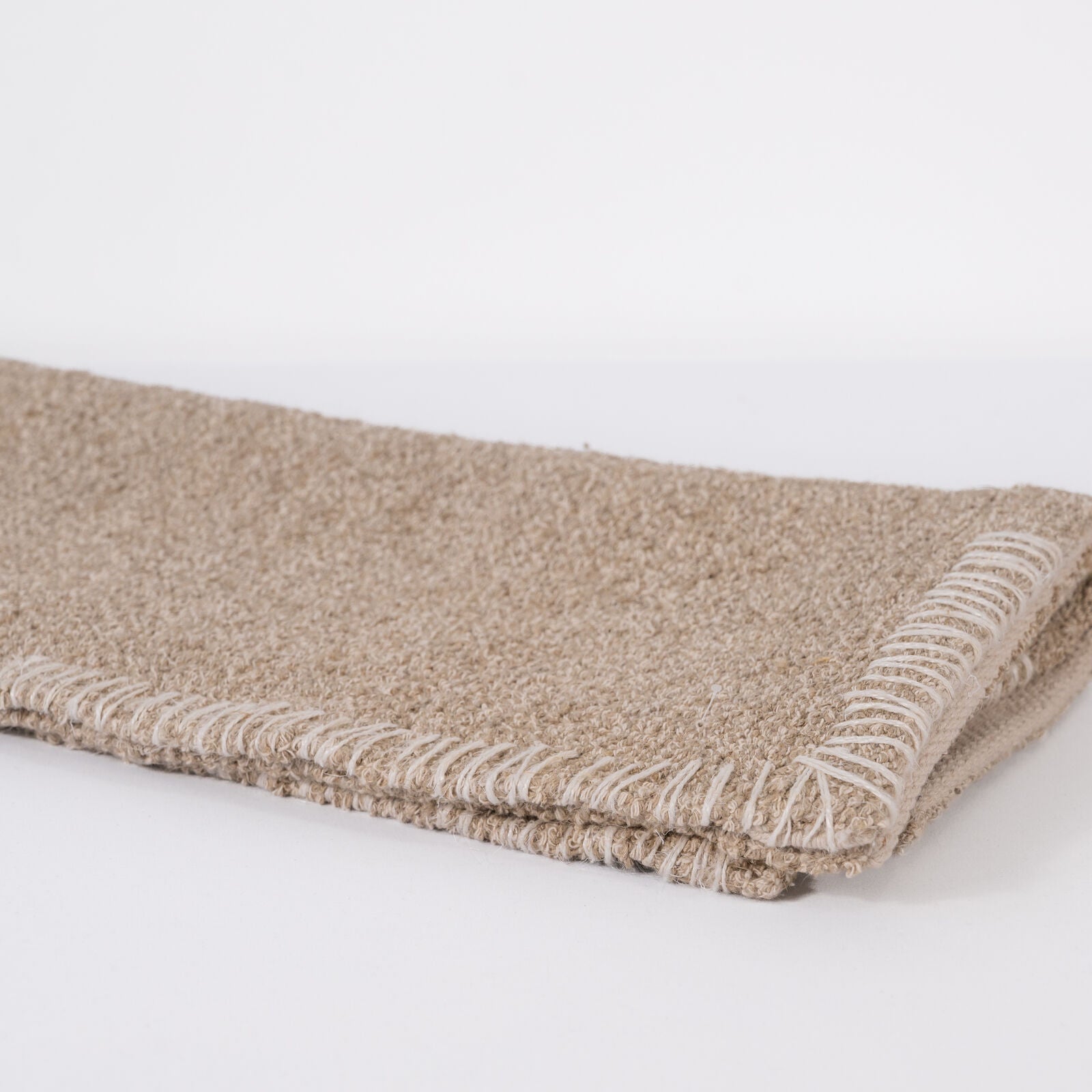 Beige woven bathmat on a white background