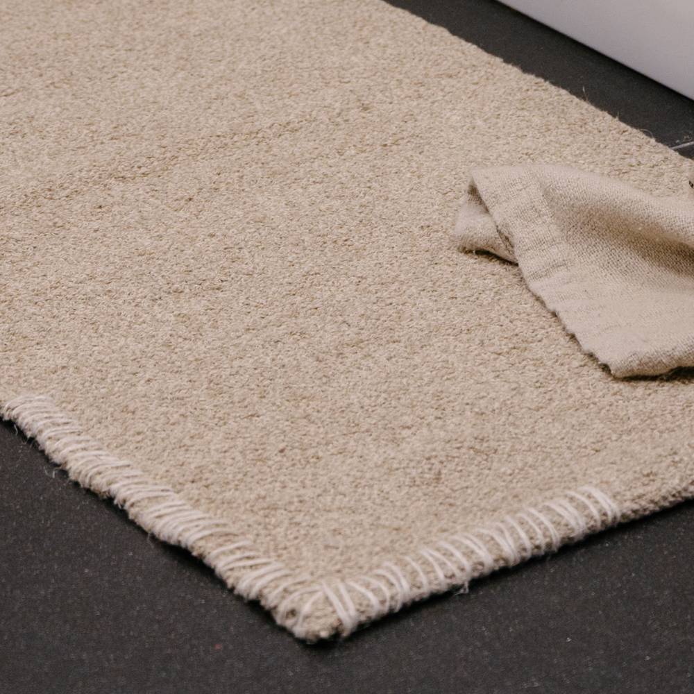 Beige handwoven bathmat rug on a black surface