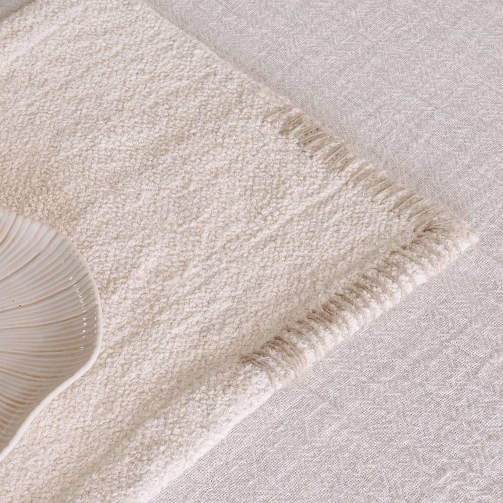 A textured cream-colored placemat with tan striped edges rests on a light-colored tablecloth