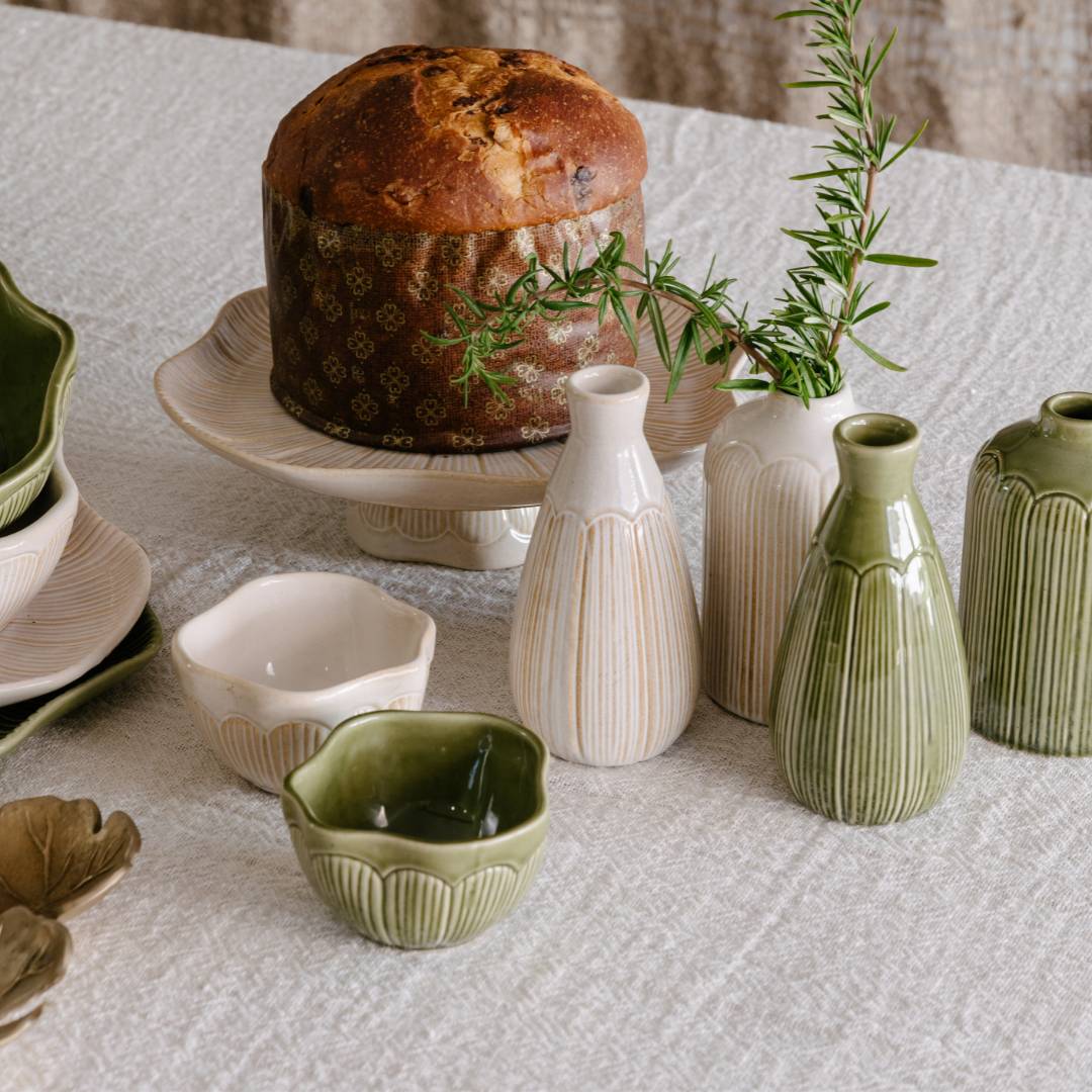 Ceramic items including vases and bowls on a textured surface with a loaf of bread.