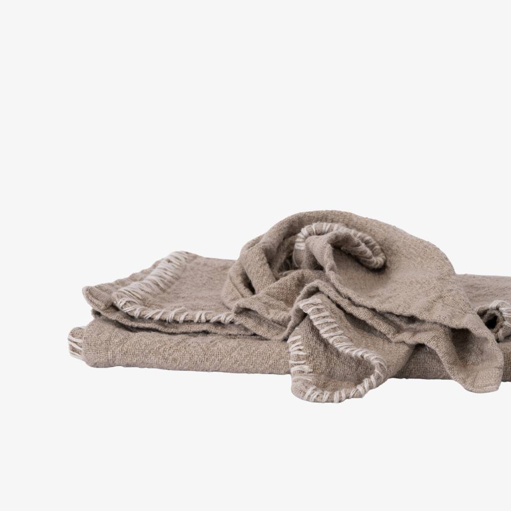 Beige blanket with frayed edges on a white background