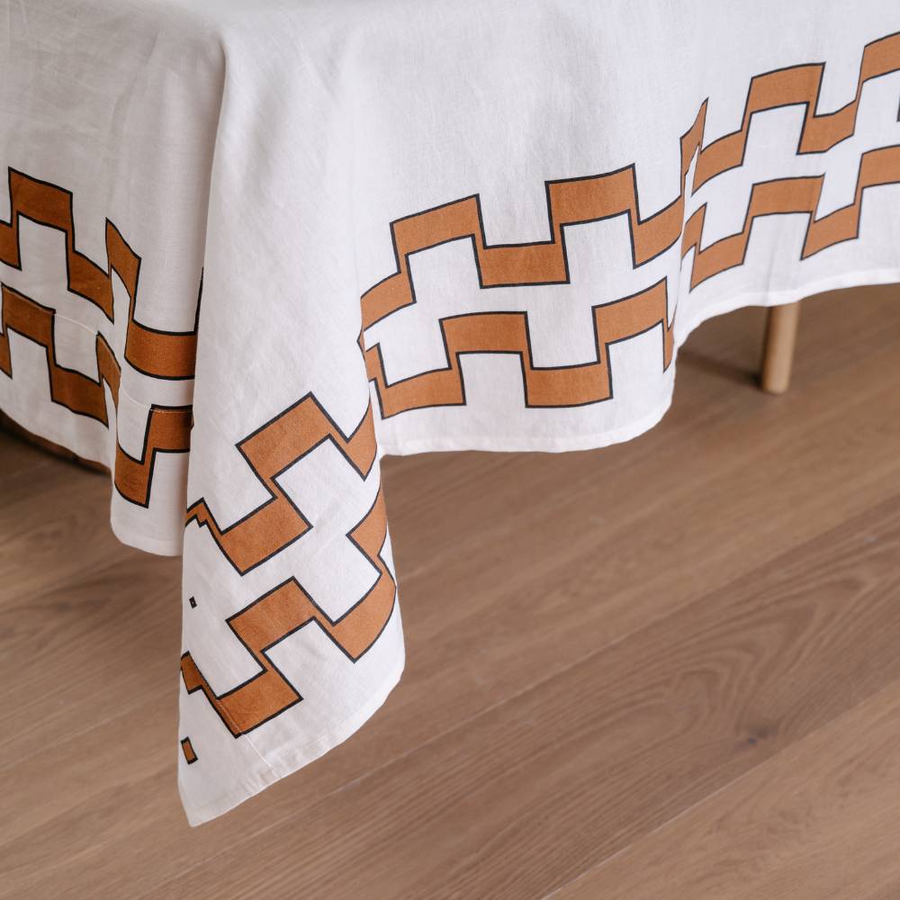 White tablecloth with nutmeg geometric pattern on a wooden surface