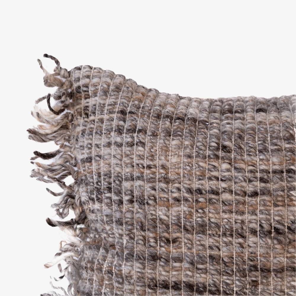 Textured woven rug with fringed edge on a white background