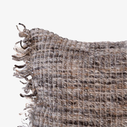 Textured woven rug with fringed edge on a white background