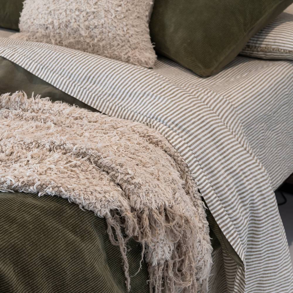 Close-up of a textured blanket draped over a sofa with striped cushions.