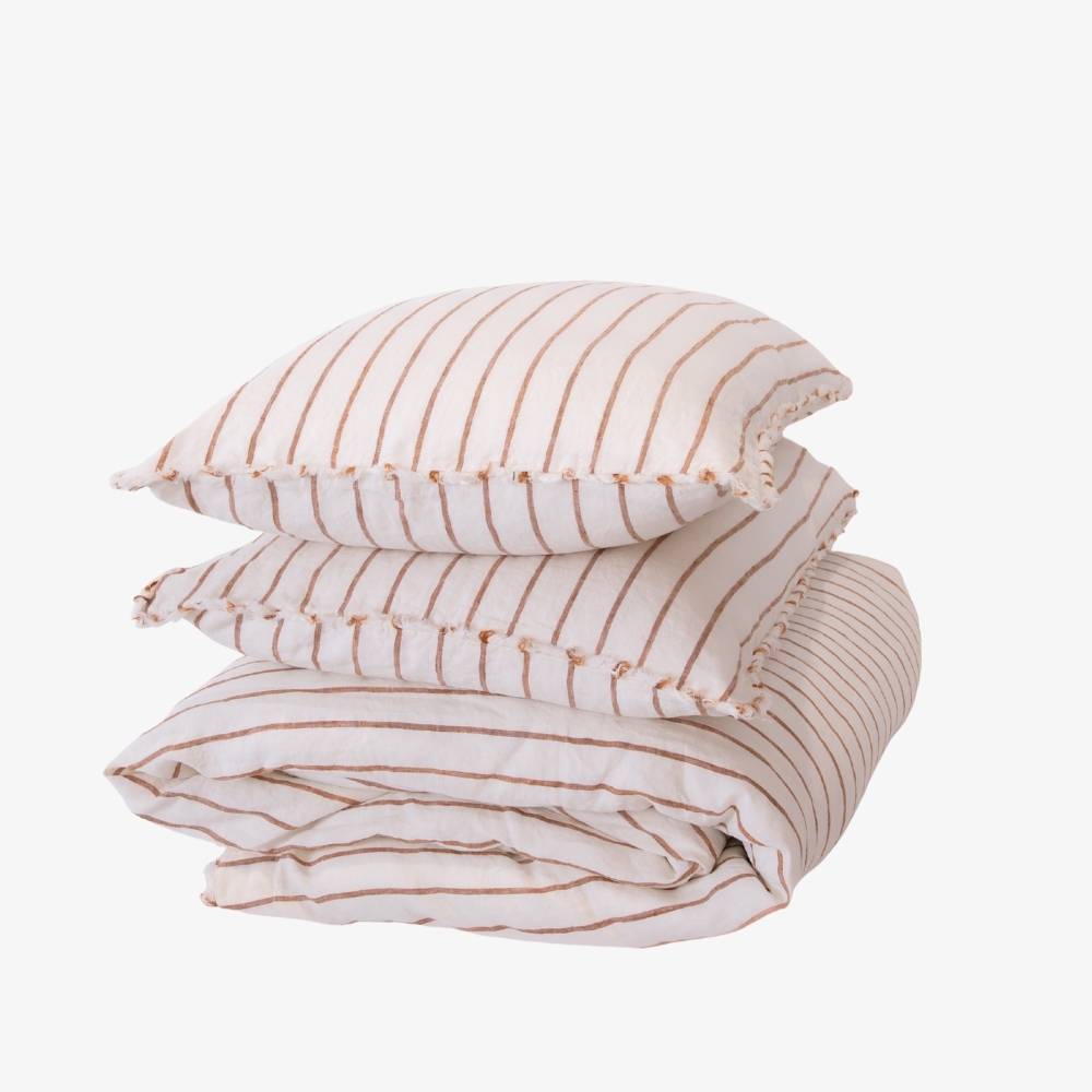 Stack of striped bedding with a pillow on a white background
