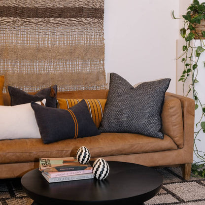 Brown leather sofa with patterned cushions in a living room setting.