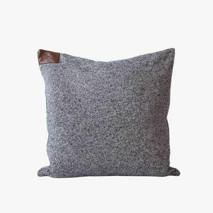 Gray textured pillow with brown leather accent on a white background