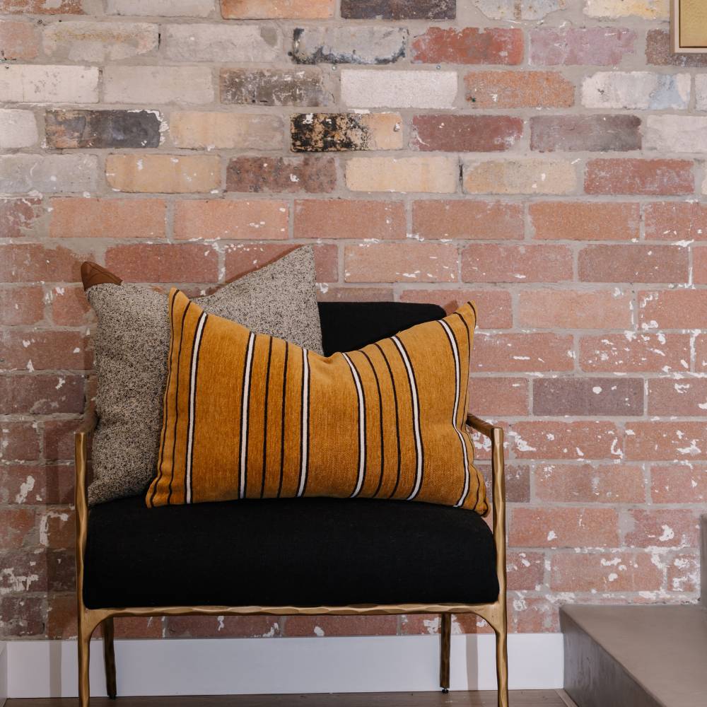 Chair with striped cushions against a brick wall