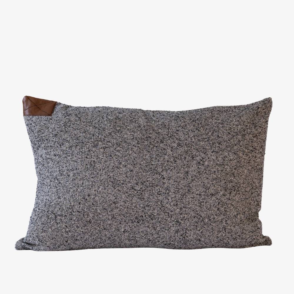Gray textured pillow with a brown leather patch on a white background