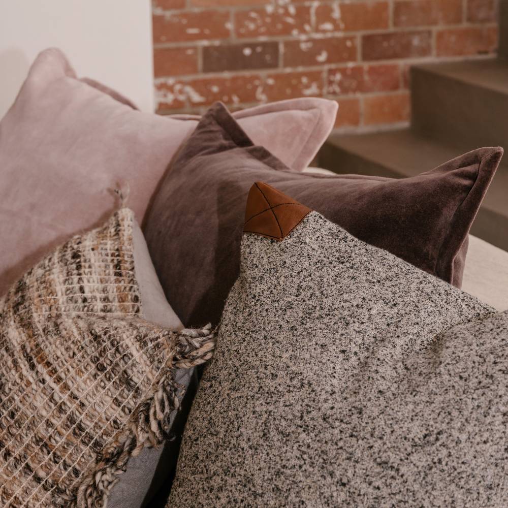 Close-up of various textured pillows on a sofa with a brick wall background