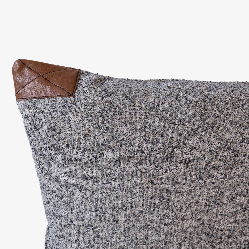 Gray textured pillow with a brown leather corner on a white background