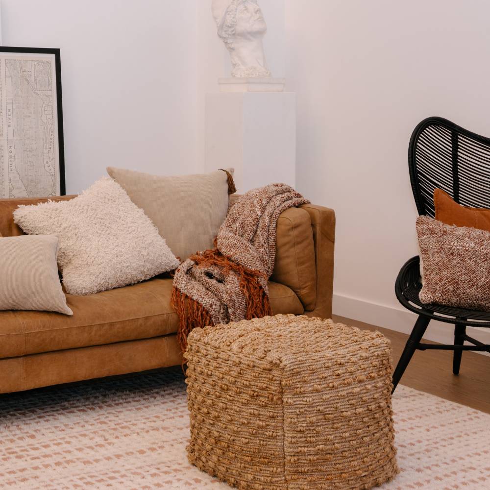Living room with brown sofa, ottoman, and chair with decorative pillows and throws.