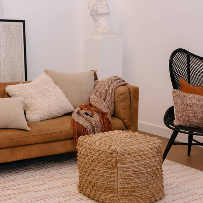 Living room with brown sofa, ottoman, and chair with decorative pillows and throws.