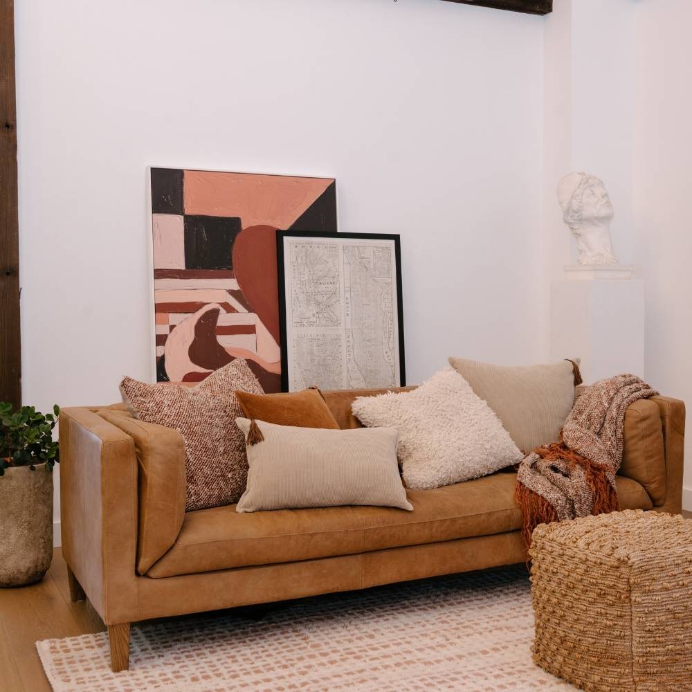 Brown sofa with decorative pillows and a textured rug in a living room setting.