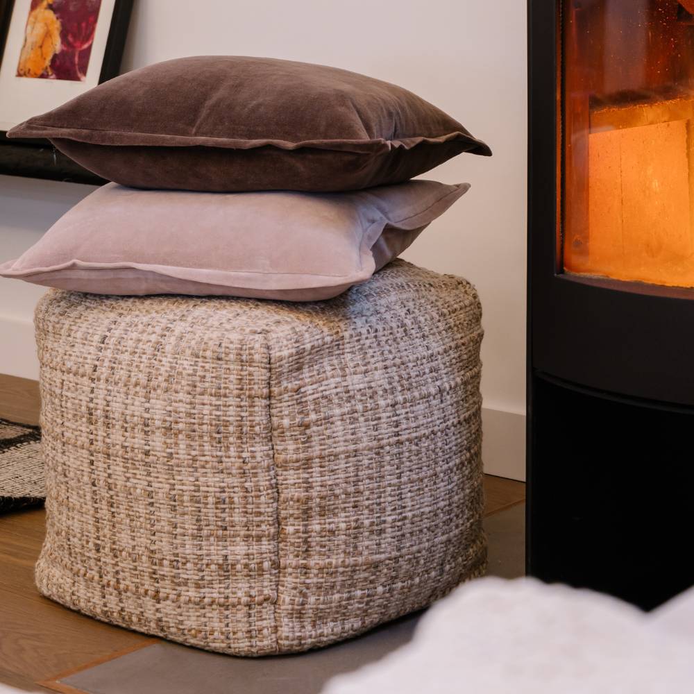 Textured ottoman with stacked cushions in a cozy room setting.
