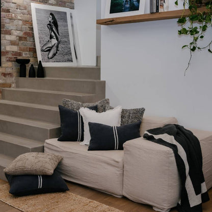 Living room with a beige sofa, decorative pillows, and a plant.