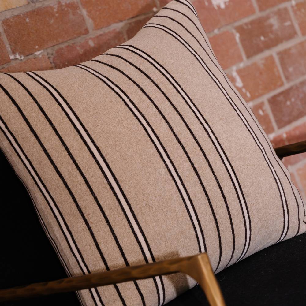 Striped pillow on a black chair with a brick wall background