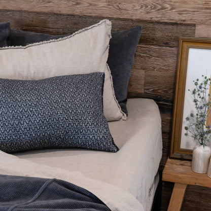Neatly arranged pillows on a bed with a wooden headboard and side table.