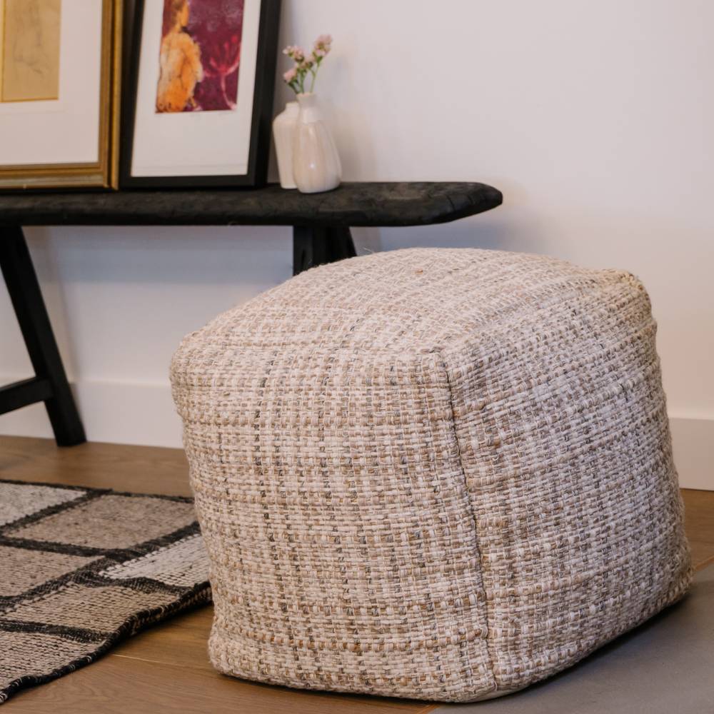 Textured ottoman in a room with a table and decorative items.