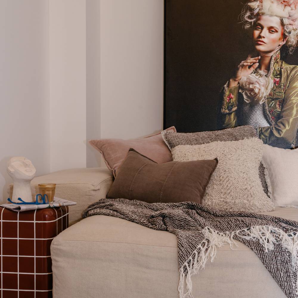 Living room with a beige sofa, decorative pillows, and a painting on the wall.