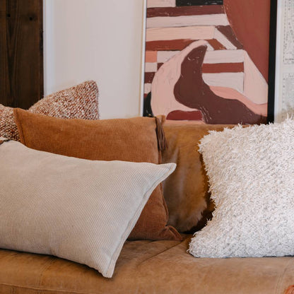 Brown sofa with textured pillows and abstract art in the background