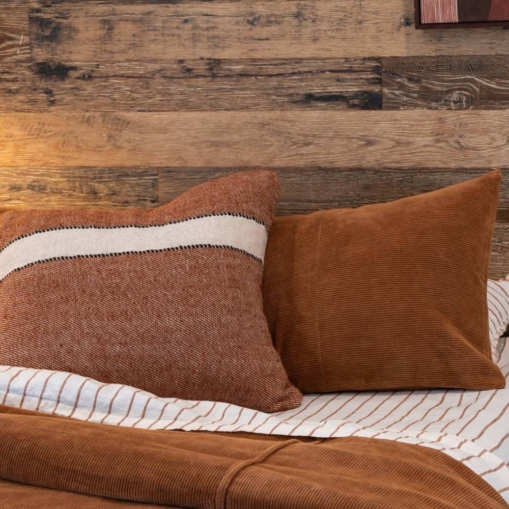 Brown textured pillows on a bed with wooden headboard