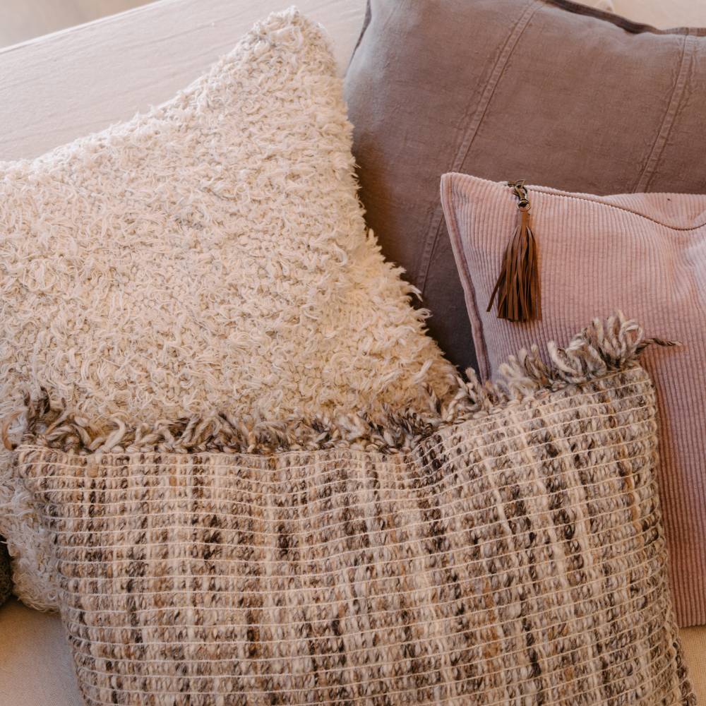 Close-up of textured pillows and a blanket on a sofa