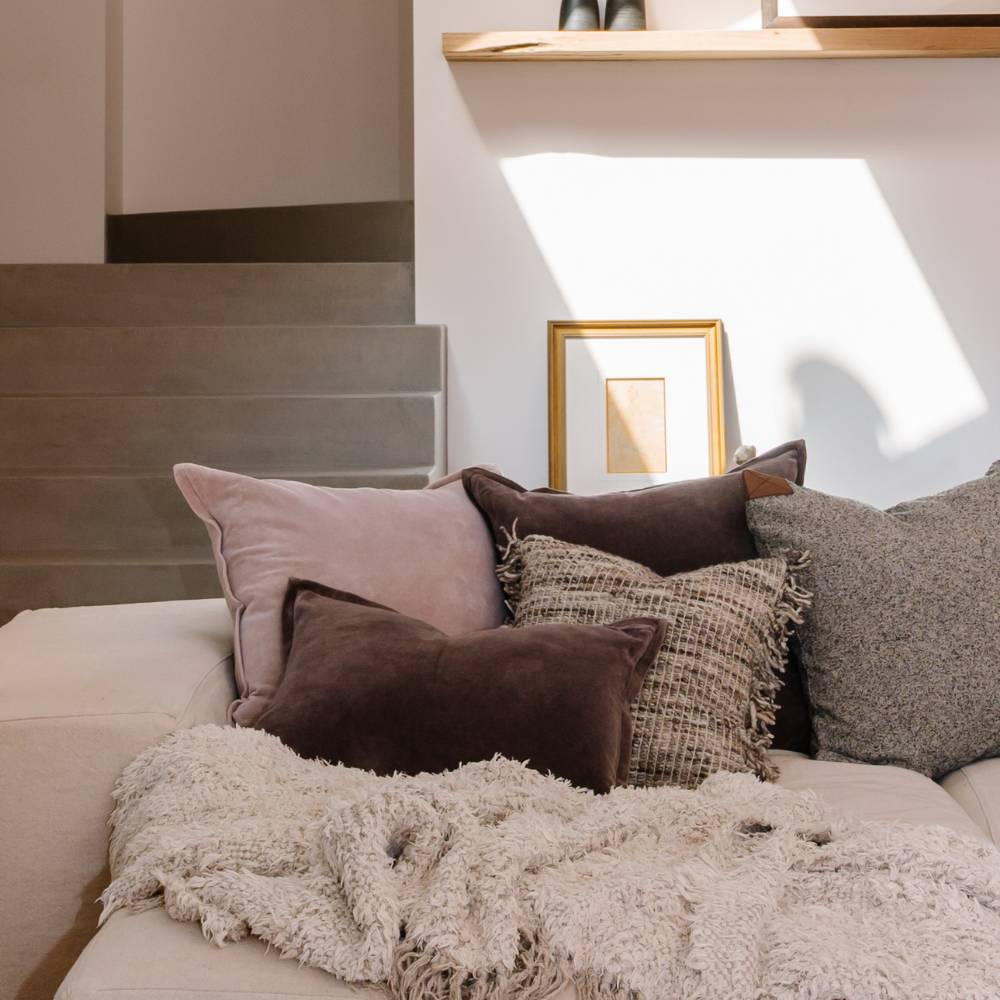 Decorative pillows on a sofa with a neutral color scheme in a home setting.