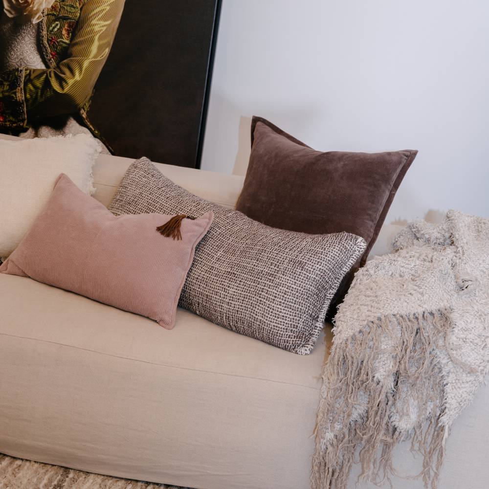 Decorative pillows on a beige sofa with a textured blanket