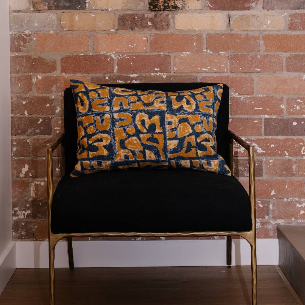 Black chair with a decorative pillow against a brick wall