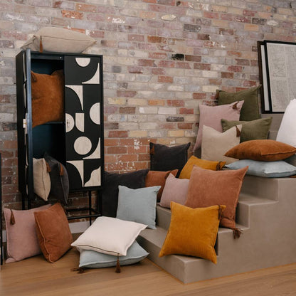 Colorful pillows on a staircase against a brick wall
