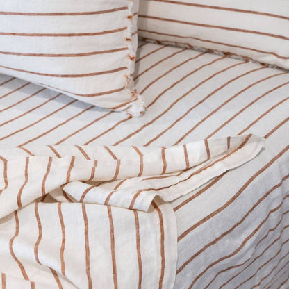 Striped bedding with white and brown lines on a bed.