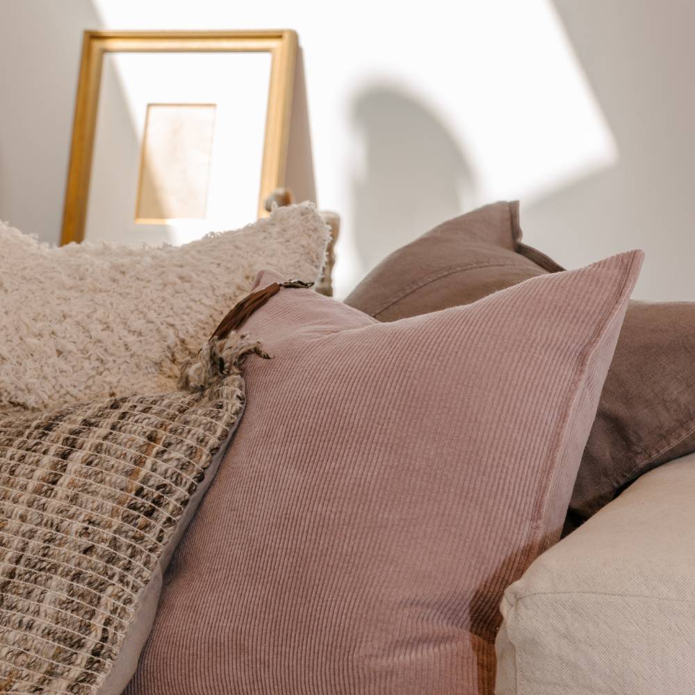Close-up of textured pillows on a sofa with a blurred mirror in the background