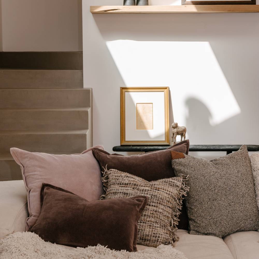 Decorative pillows on a sofa with a framed picture on a table in the background.