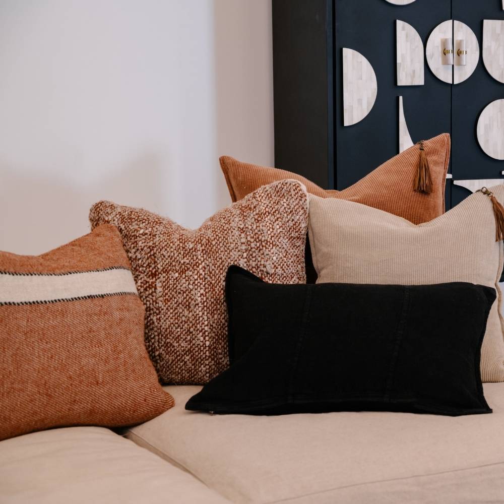 Decorative pillows on a sofa with a modern wall art piece in the background