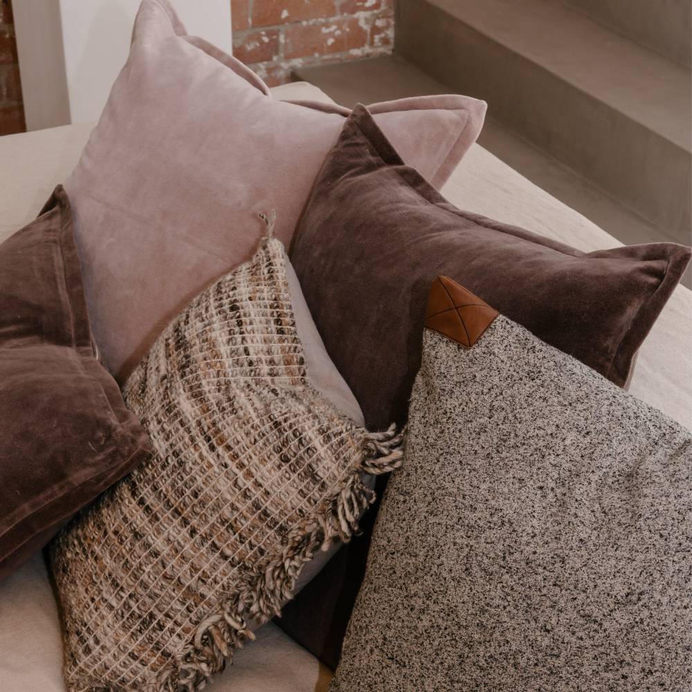 Assorted pillows on a sofa with a neutral background