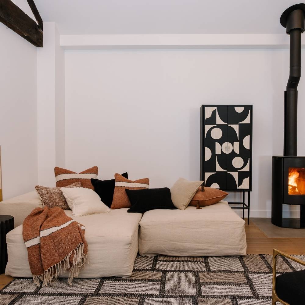 Modern living room with a white sofa, decorative pillows, and a fireplace.