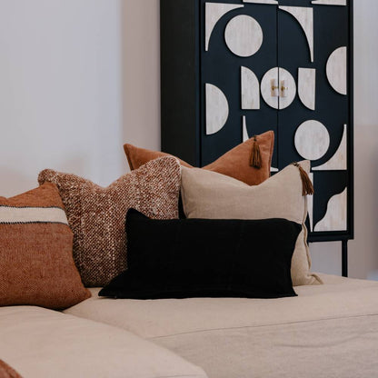 Decorative pillows on a bed with a geometric wall art piece in the background