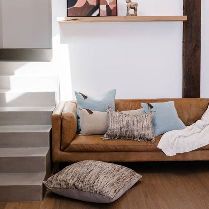 Brown leather sofa with decorative pillows in a living room setting.