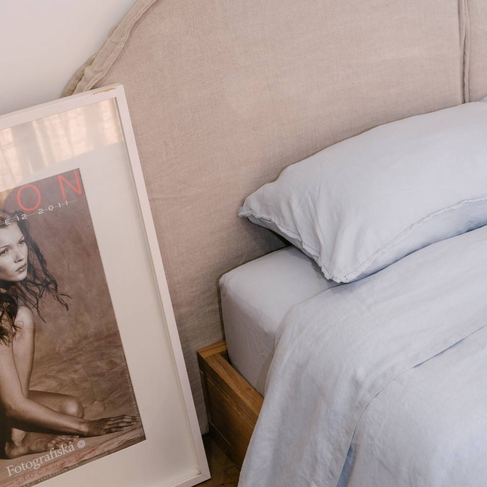 Framed magazine on a nightstand next to a bed with light blue bedding.