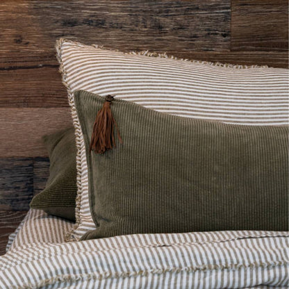 Two pillows, one green and one striped, on a bed with a wooden headboard.