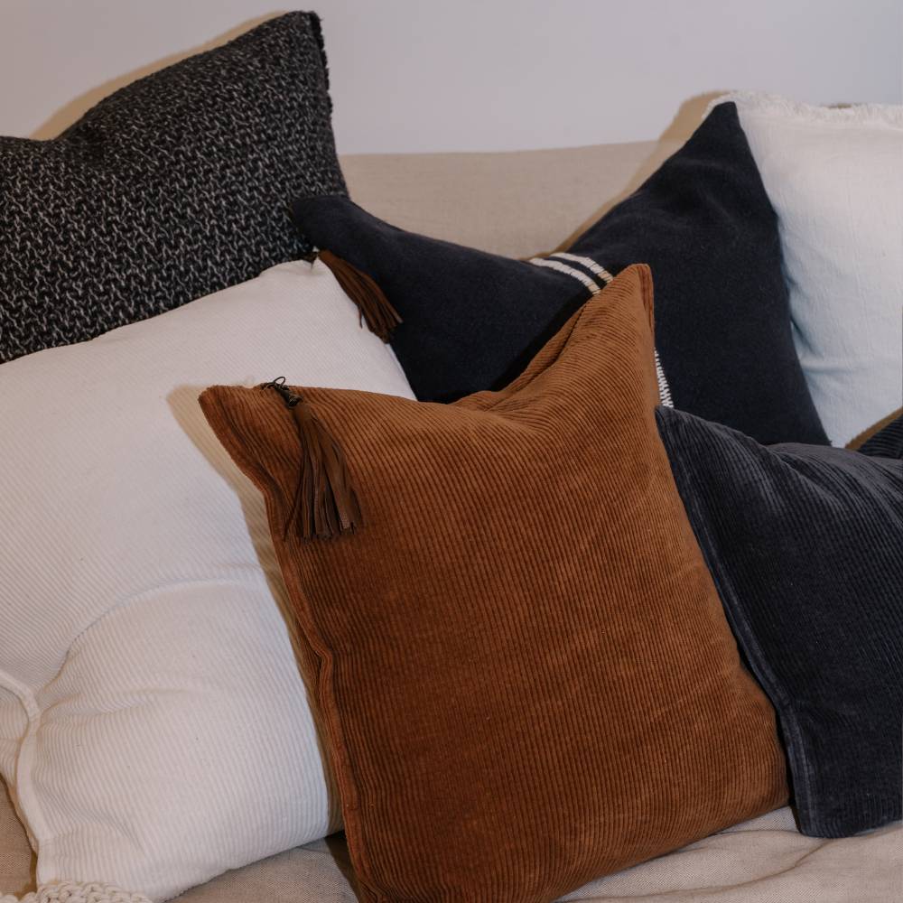 Collection of various pillows on a sofa with a neutral background